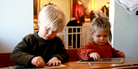 To små børn skriver på tavle i den gamle skolestue