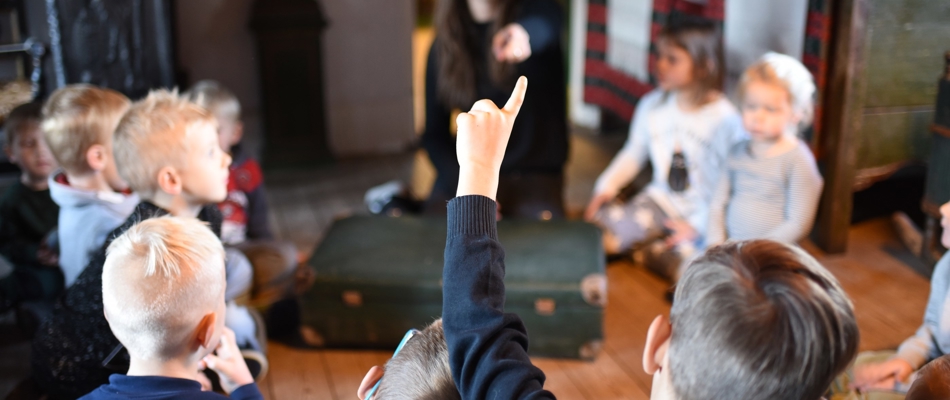 Undervisning i stuehuset, hvor elever rækker fingeren op