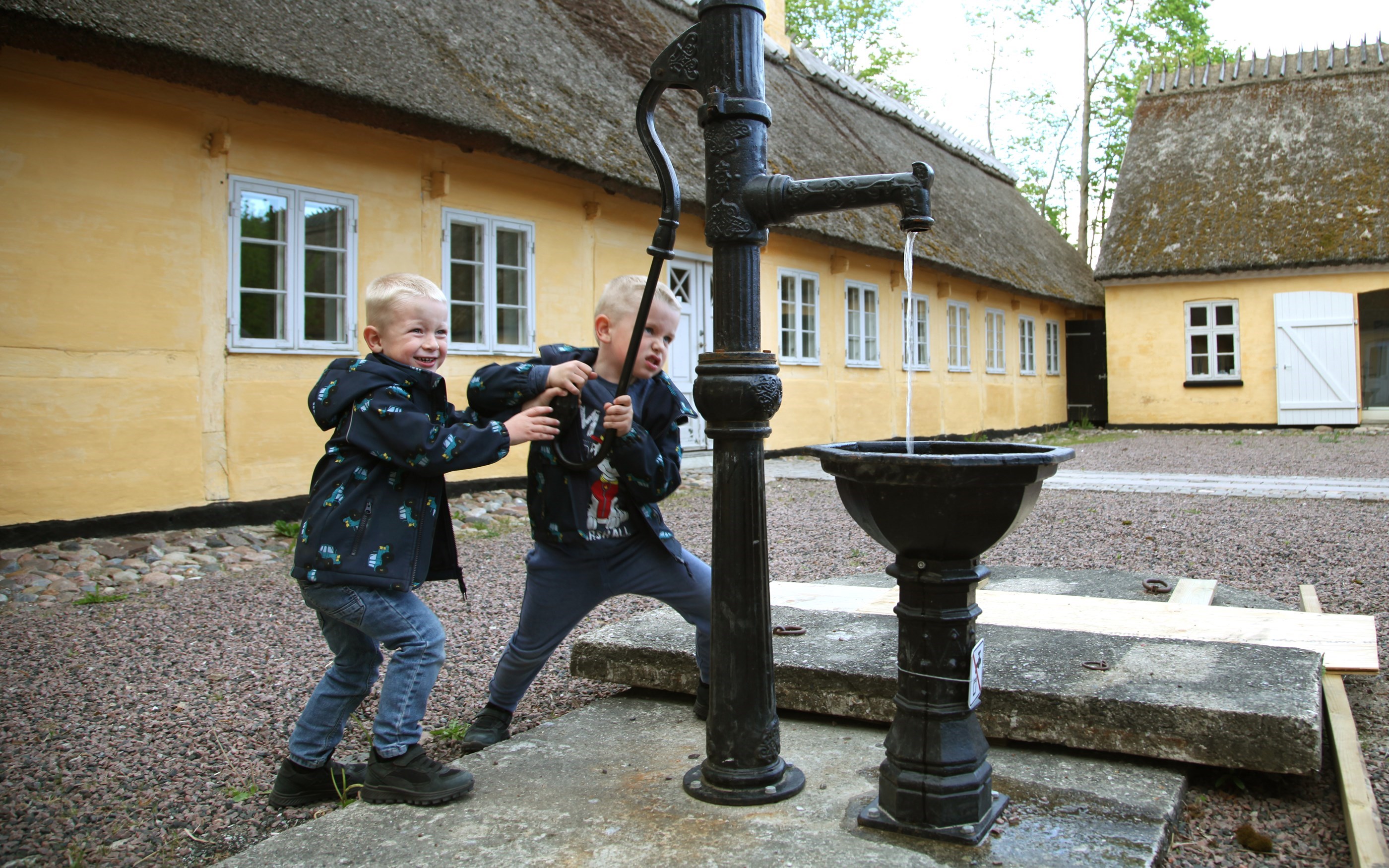 Drenge og vandpumpe på gårdspladsen på Greve Museum