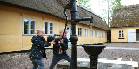 Drenge og vandpumpe på gårdspladsen på Greve Museum