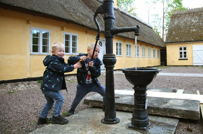 Drenge og vandpumpe på gårdspladsen på Greve Museum